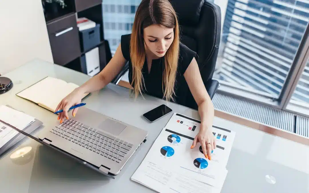 female businesswoman readind financial report analyzing statistics pointing at pie chart working at her desk