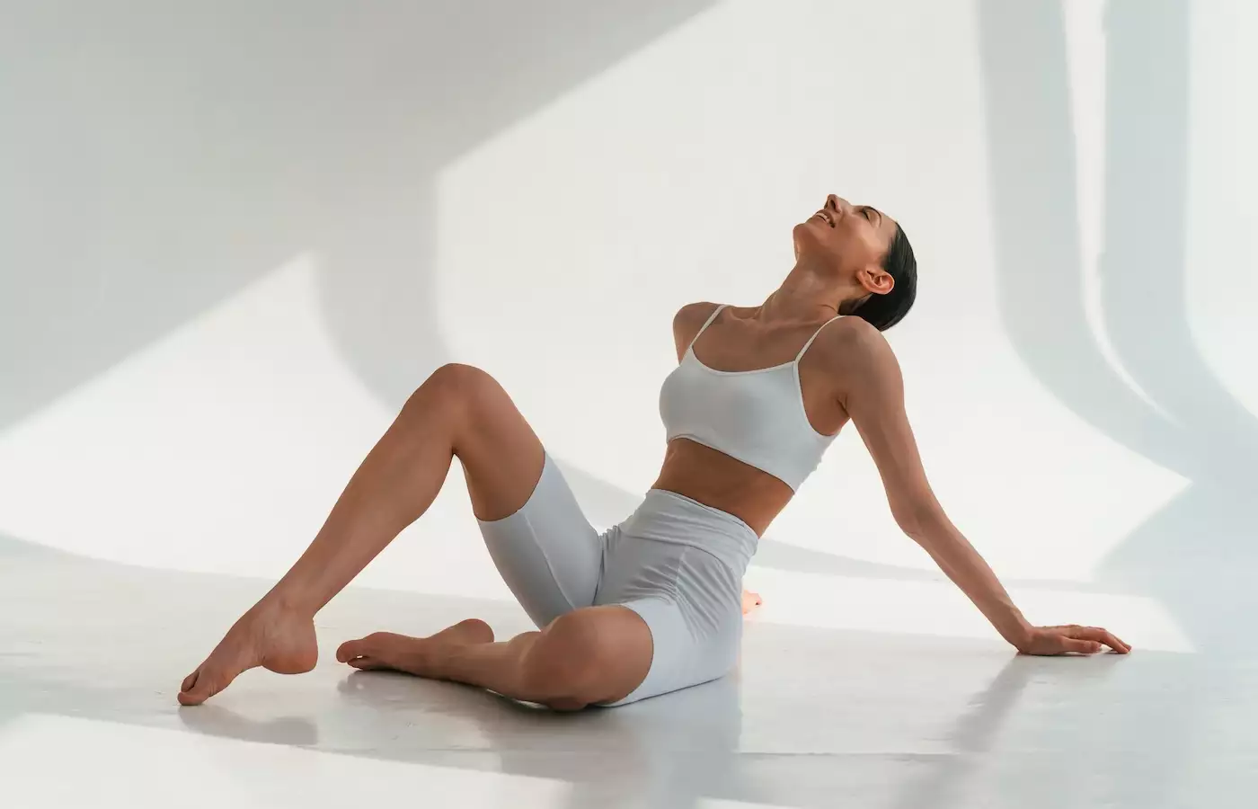 beautiful toned young woman in white workout set on floor